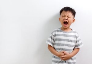 Little Asian boy having abdominal pain, isolated on white background.